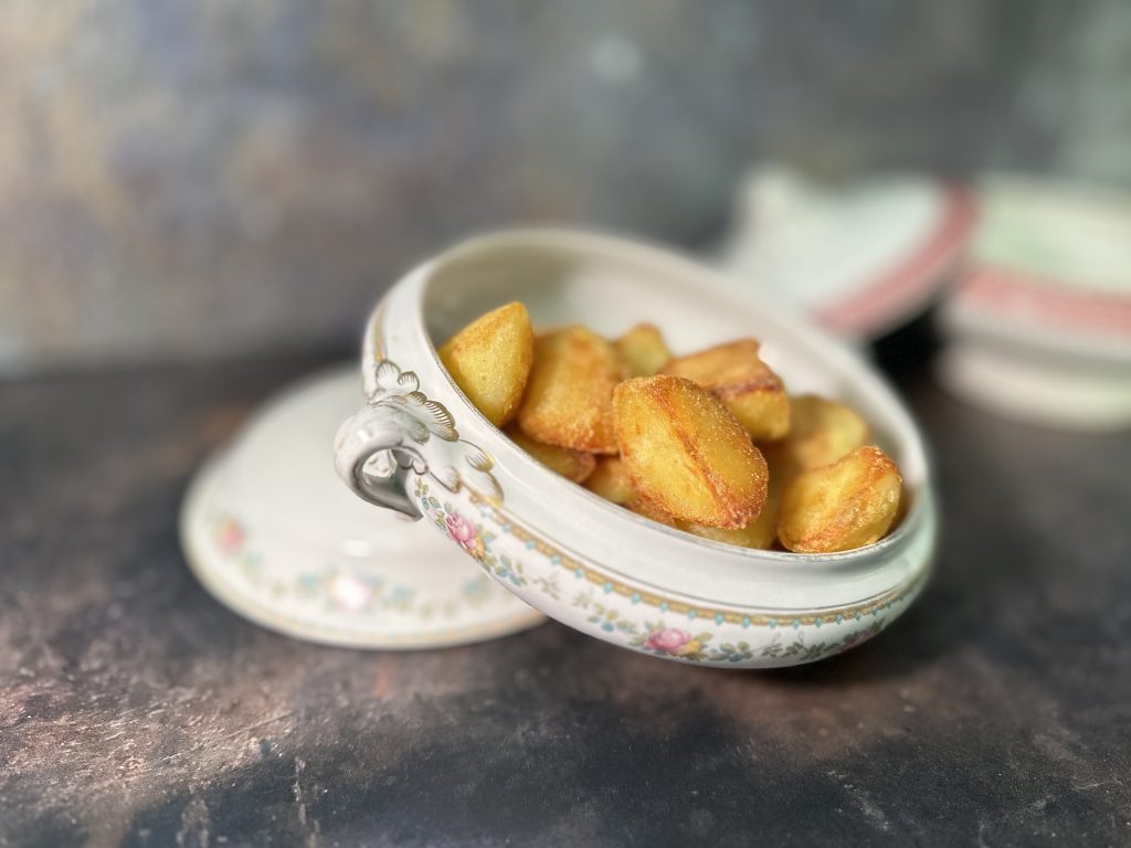 Beautiful old-fashioned vegetable dish with the lid off to show crispy crunchy roast potatoes