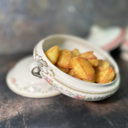 Beautiful old-fashioned vegetable dish with the lid off to show crispy crunchy roast potatoes