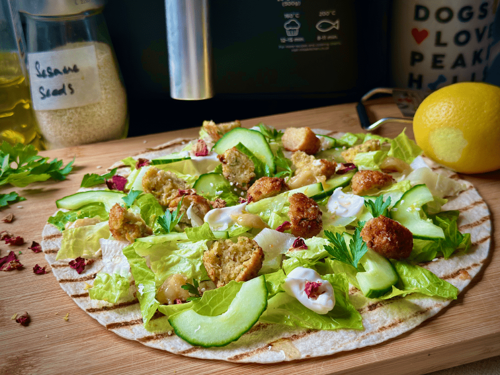 Image of flatbread on a chopping board with salad and chunks of falafel