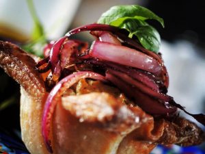 Close up of red onion and basil on top of an individual puff pastry tart