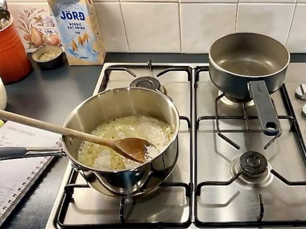 Pan of melted butter with flour on a stainless steel hob with a wooden spoon in the pan