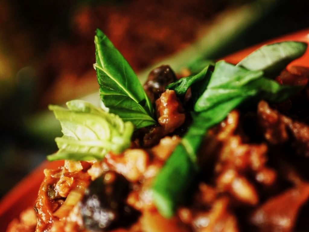 Close up of basil leaves on top of bolognese sauce on top of spaghetti