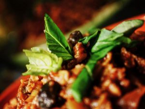 Close up of basil leaves on top of bolognese sauce on top of spaghetti