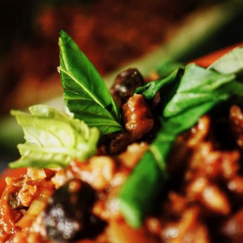 Close up of basil leaves on top of bolognese sauce on top of spaghetti