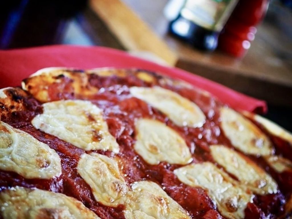 A close up photo of fresh pizza covered with tomato sauce and lots of mozzarella slices