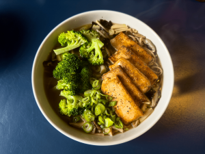 Vegan Ramen: noodles in a clear both, topped with pan-fried tofu, served with broccoli and chopped spring onions