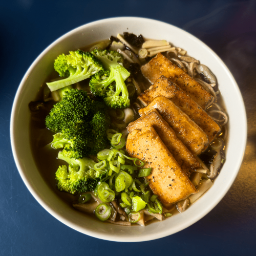 Vegan Ramen: noodles in a clear both, topped with pan-fried tofu, served with broccoli and chopped spring onions