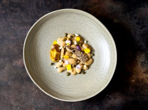A warm bowl of butterbeans and capers in a golden broth, infused with dried lime – comfort food with depth and tenderness.