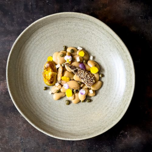 A warm bowl of butterbeans and capers in a golden broth, infused with dried lime – comfort food with depth and tenderness.