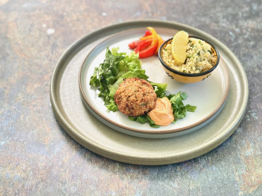 Golden lentil koftas on salad leaves with a swirl of harissa mayo and lemon wedges on the side
