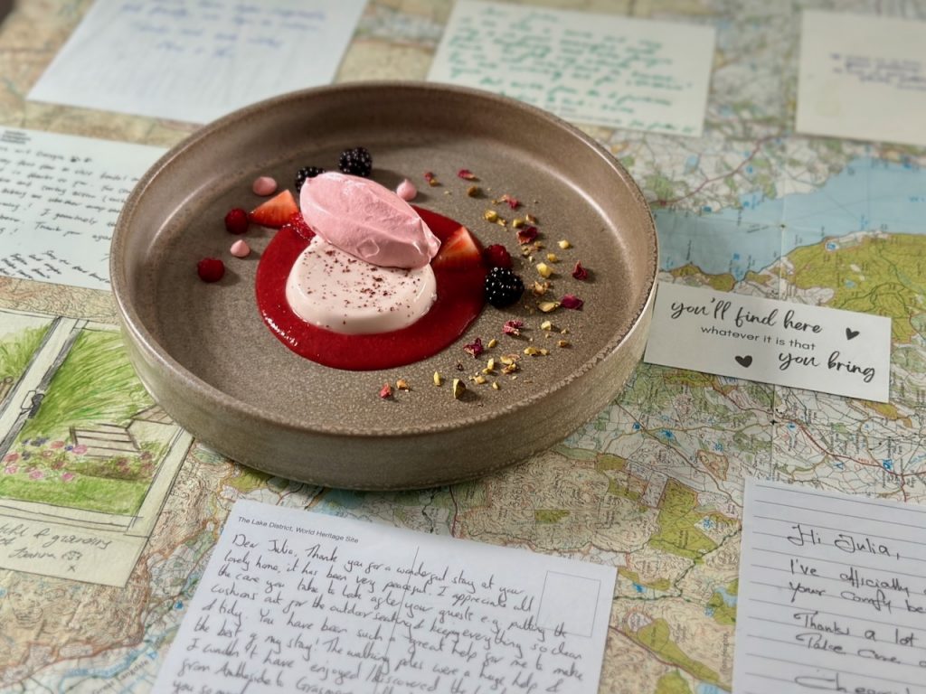 A vegan dessert. Pink meringue sitting on white panna cotta which is sitting on a round pool of strawberry coulis