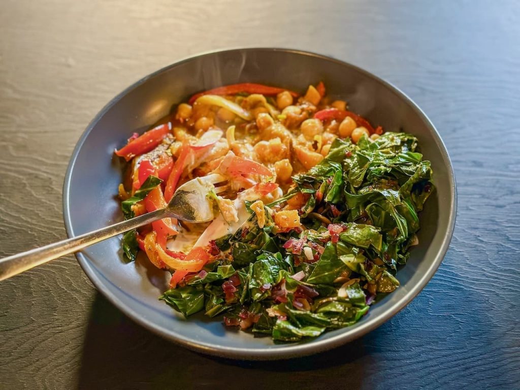 bowl of butternut squash and red pepper tagine with spring greeens alongside. Bright and appetising. A perfect winter dish.