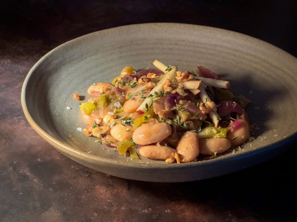 a cosy grey bowl of cider-braised butterbeans dressed with shards of red apple and pear, with lots of fresh thyme.